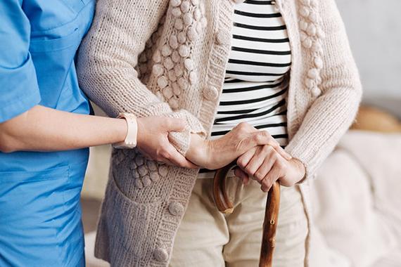 Nurse assists woman with cane